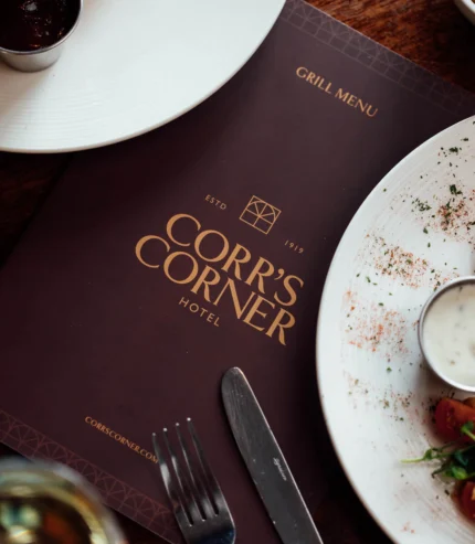 Elegant restaurant table setting with gourmet dishes, inviting menu, and fine cutlery at Corr's Corner Hotel.